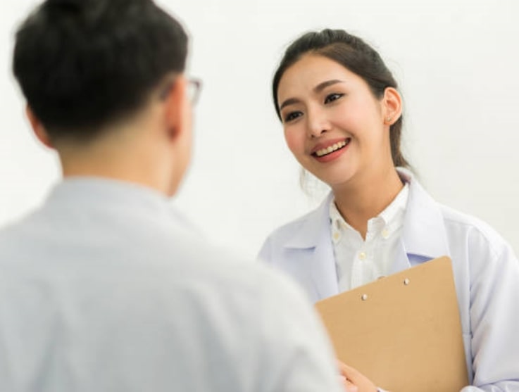 Oriental female doctor smiling to a male patient
