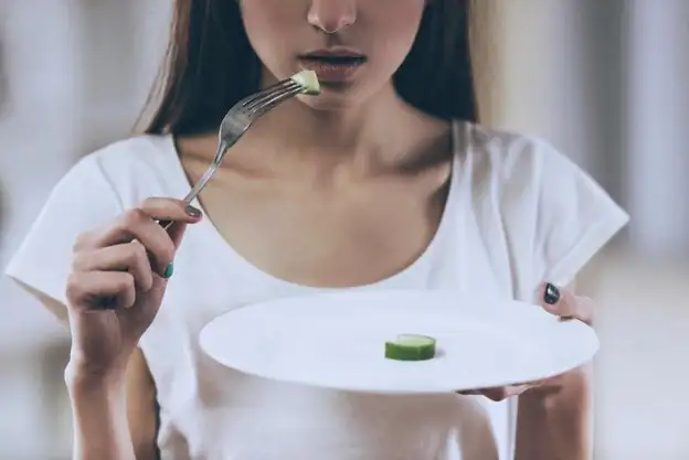 young woman eating a slice of cucumber